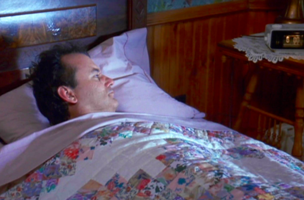 Bill Murray in Groundhog Day, waking up next to the alarm clock